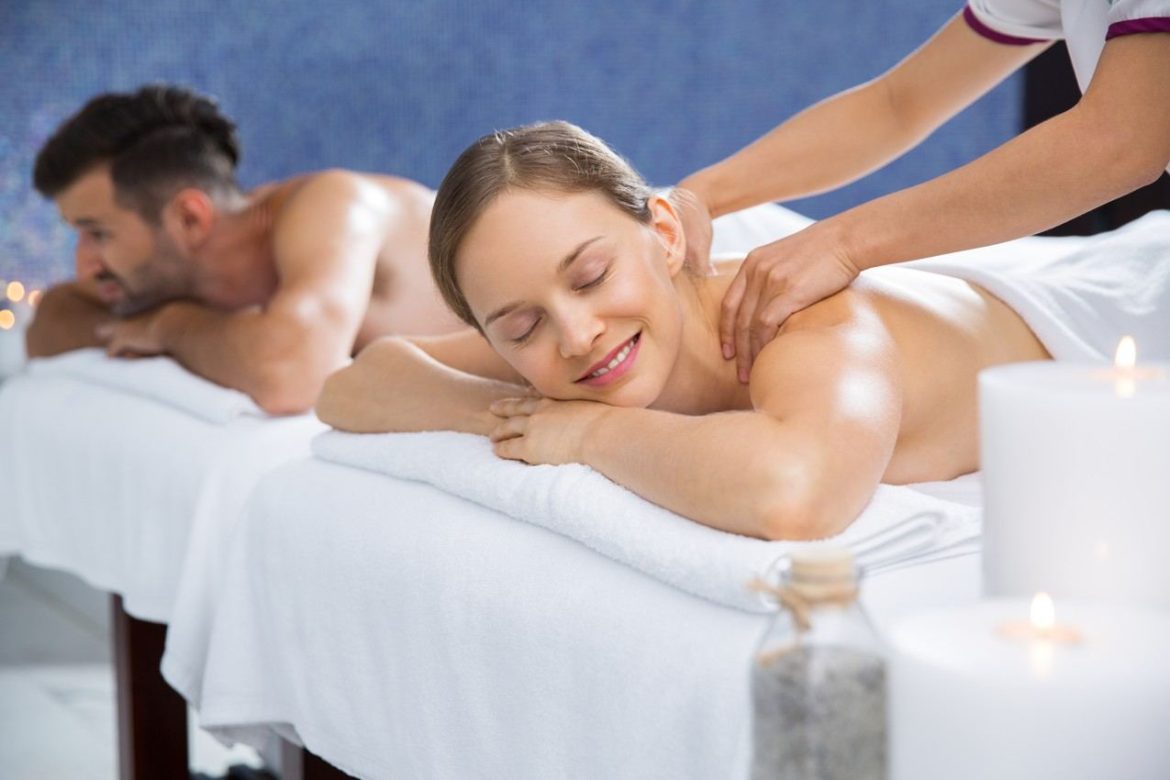 Couple profitant d'un massage romantique bougies dans un spa apaisant.